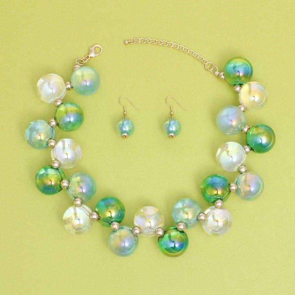 Women's blue green iridescent bubble ball bead necklace set with matching earrings on green background.